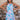 Front view of model wearing the Bahama Blues Floral Dress that has blue fabric with a pink, light blue, light pink and tan floral pattern, mini length, a halter neck, a sleeveless design, and a back keyhole with a tie closure.