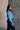 Side view of model wearing the Gabriela Blue Turtleneck Sweater that has blue knit fabric, ribbed hem, a turtleneck neckline, dropped shoulders, and long sleeves with cuffs.
