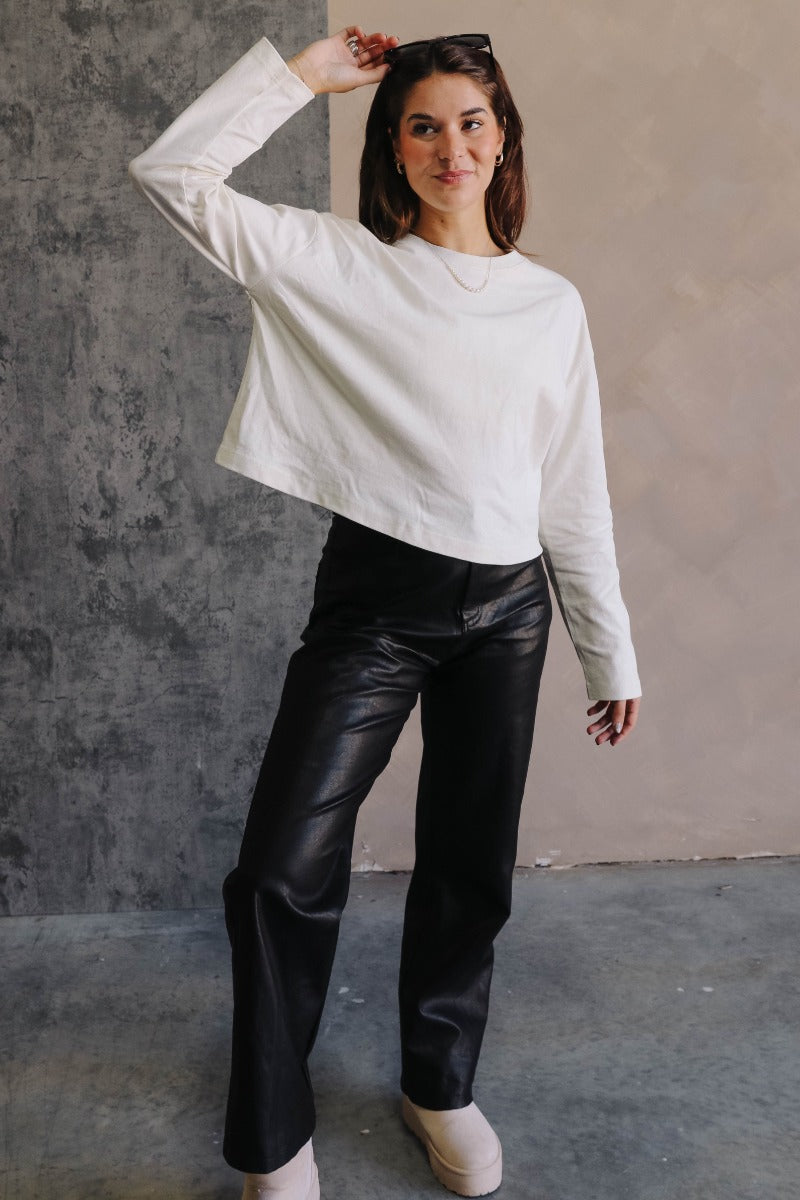 Full body view of model wearing the Nikole Cream Cropped Long Sleeve Sweatshirt which features cream cotton fabric, cropped waist, round neckline and long sleeves.