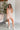 Full body front view of model wearing the Laguna Floral Romper that has denim fabric with an orange, pink, aqua, green and blue floral print, folded hem, two front chest pockets, side and back pockets, snap up buttons, a collared neck, and short sleeves