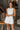 Front view of model wearing the Never Out Of Style Romper which features white fabric, side pockets, a sleeveless design, a round neckline, and a monochromatic back zipper with a hook closure.