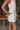Close up side view of model wearing the Never Out Of Style Romper which features white fabric, side pockets, a sleeveless design, a round neckline, and a monochromatic back zipper with a hook closure.