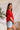 Side view of model wearing the Let's Dance Ruffle Sleeve Top that has red semi-sheer fabric, a round neckline, ruffle tiered short sleeves, and a back keyhole with a button closure.