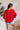Full body back view of model wearing the Let's Dance Ruffle Sleeve Top that has red semi-sheer fabric, a round neckline, ruffle tiered short sleeves, and a back keyhole with a button closure.