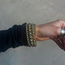Close up view of model wearing the Naomi Gold Bead Layered Wrap Bracelet which features spiral bangle with gold beads.