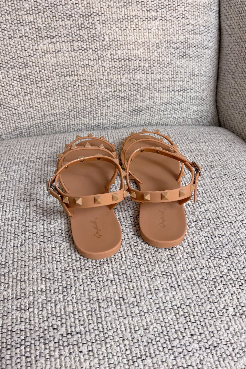 Heel view of the Now or Never Sandals which features matte peach coloring, pc upper, monochromatic studs and adjustable buckle straps. 