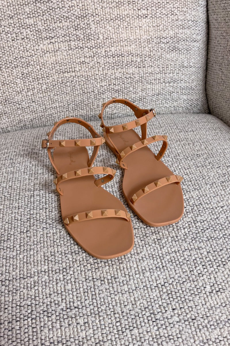 Full view of the Now or Never Sandals which features matte peach coloring, pc upper, monochromatic studs and adjustable buckle straps. 
