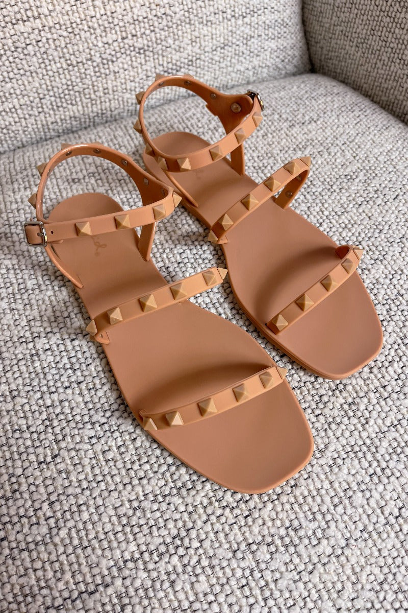 Close up view of the Now or Never Sandals which features matte peach coloring, pc upper, monochromatic studs and adjustable buckle straps. 