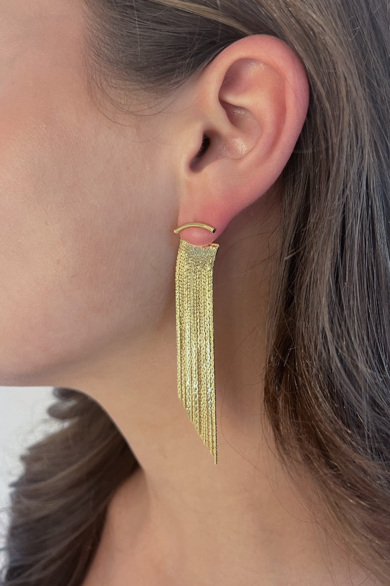 Side view of model wearing the Glam It Up Earrings which features gold fringe dangle details.