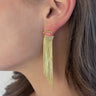 Side view of model wearing the Glam It Up Earrings which features gold fringe dangle details.