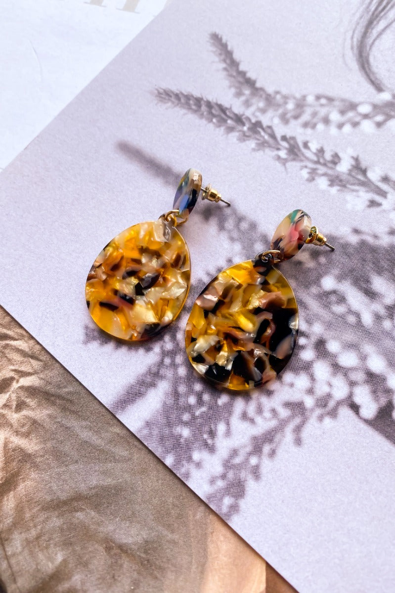 The Talk The Talk Earring is a dangle style earring featuring a tortoiseshell design with a multi-colored stud.