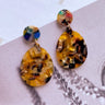 The Talk The Talk Earring is a dangle style earring featuring a tortoiseshell design with a multi-colored stud.