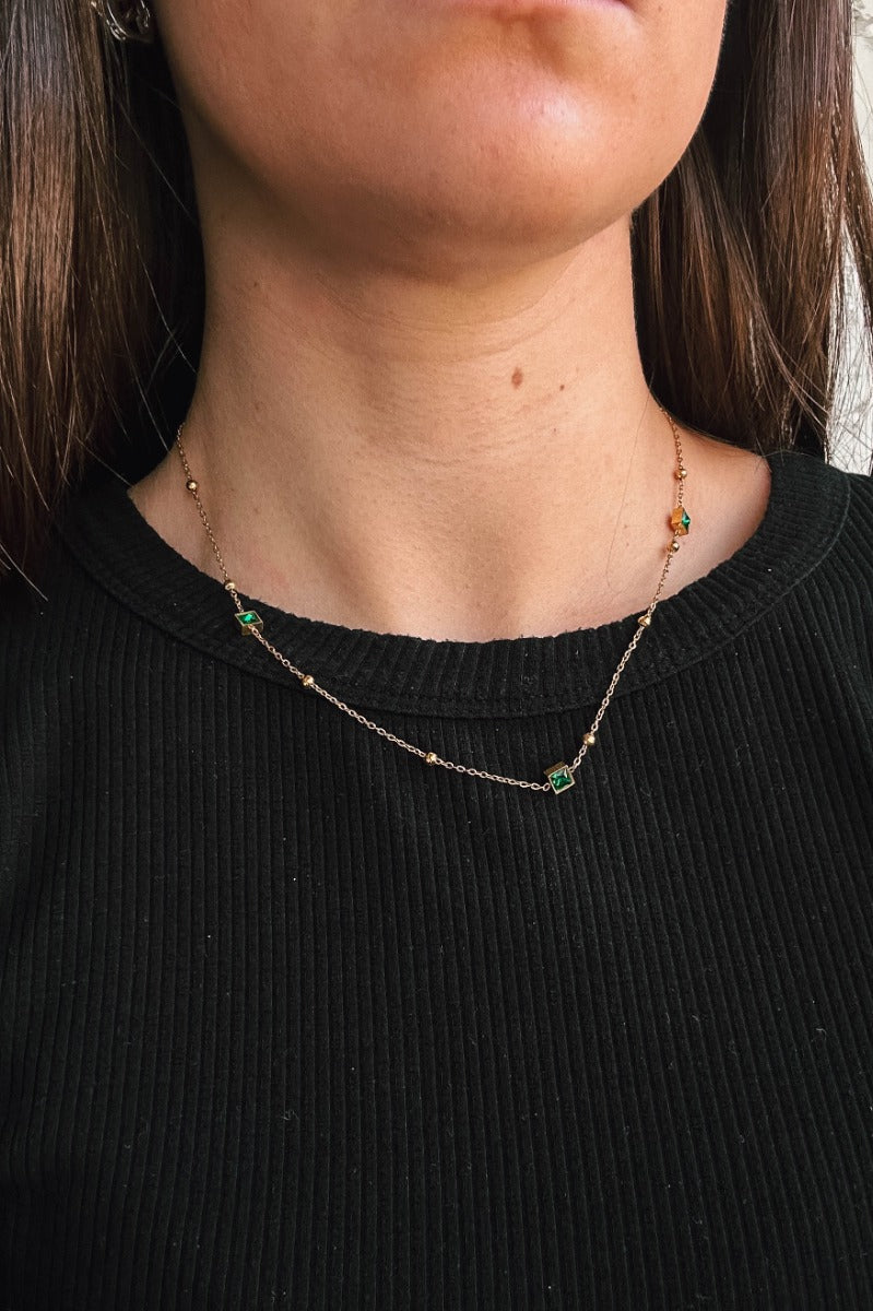Front view of model wearing the Eliza Green Stones Gold Necklace which features single gold chain link layer with square shaped green stones and gold beads.