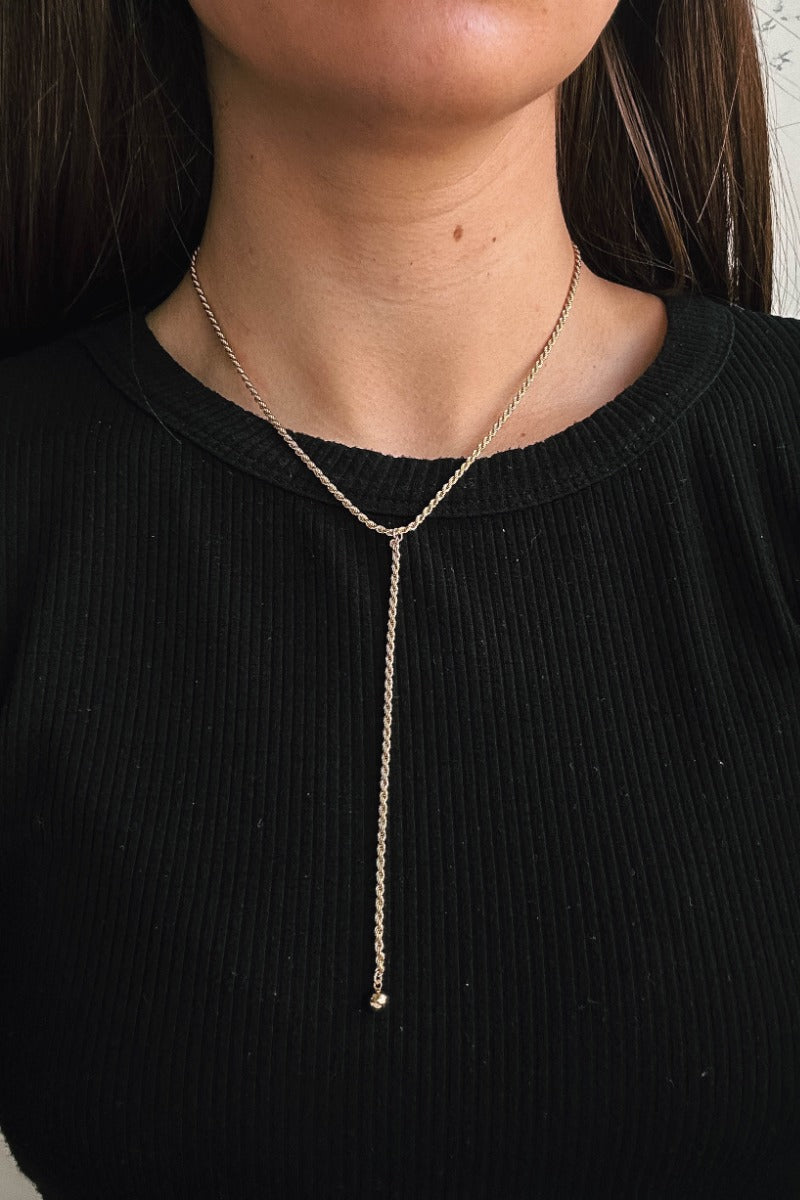 Front view of model wearing the Cecilia Gold Roped Lariat Necklace which features single gold roped layer with a gold bead attachment.