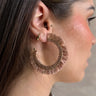 Side view of model wearing the Santa Cruz Hoop Earring in Mauve which features large, open hoop with mauve fringe design with gold and mauve beads.