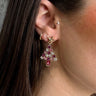 Close up view of model wearing the Pink Multi Christmas Tree Earring which features purple, pink and clearr stones shaped as a christmas tree with a gold star.