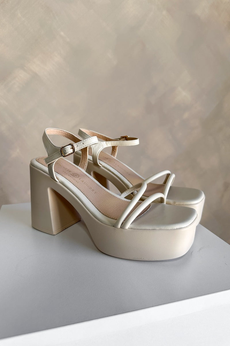 Front right angle view of the Avianna Block Heel in Cream which features cream matte faux-leather, 1.75" platforms, 4.25" heels, criss-cross straps across the toes, and ankle straps with adjustable buckle closures.
