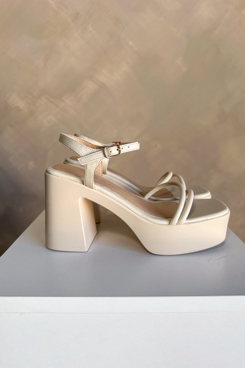 Side view of the Avianna Block Heel in Cream which features cream matte faux-leather, 1.75" platforms, 4.25" heels, criss-cross straps across the toes, and ankle straps with adjustable buckle closures.