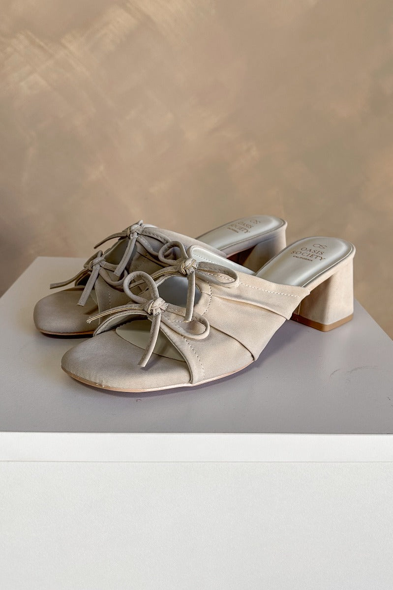 Side view of the Emerald Light Grey Bow Ties Heel Sandal which features grey suede material, 2.5" block heels, backless slide entry, and ruched uppers with a cutout and bow details.