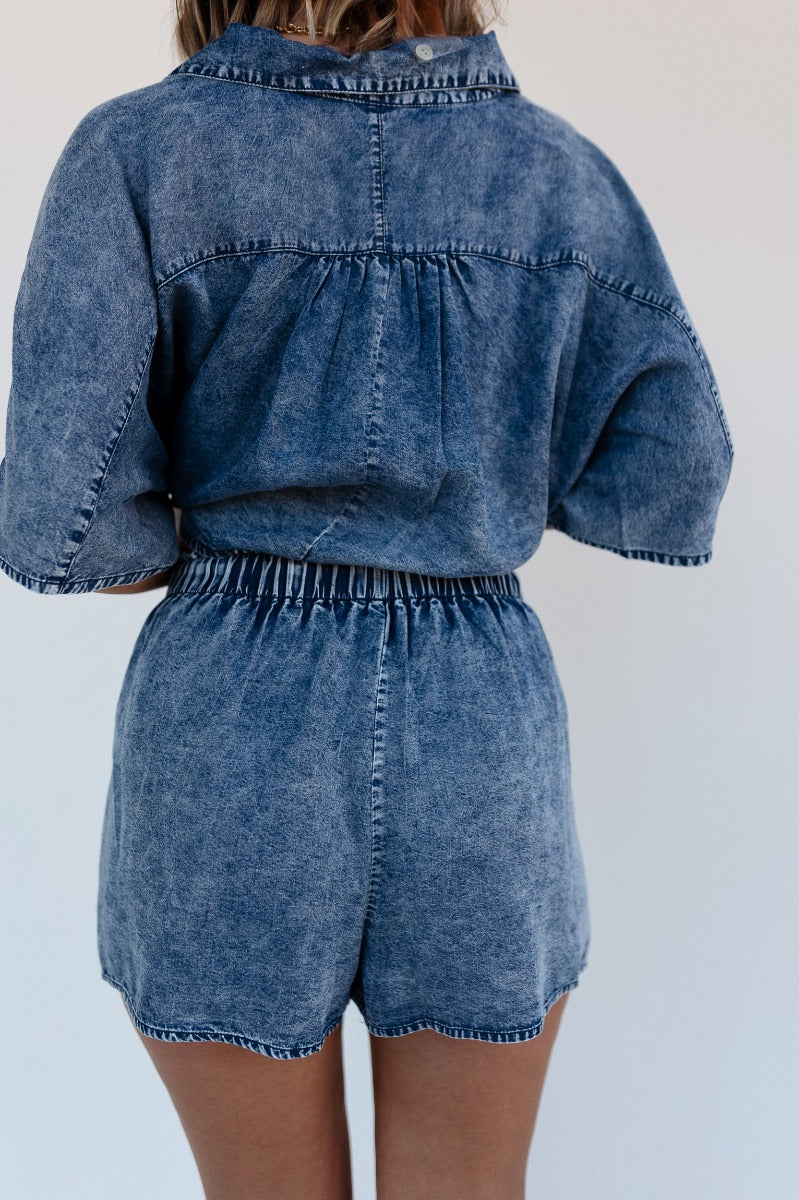Back view of model wearing the Jade Washed Denim Elastic Shorts which features washed denim tencel fabric, two front pockets and elastic waistband wih drawstring ties.