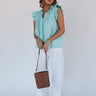 Full body front view of model wearing the Emory Aqua Sleeveless Ruffle Top that has aqua blue cotton fabric, a ruffled notched neckline with ties, and a sleeveless body with ruffle details.
