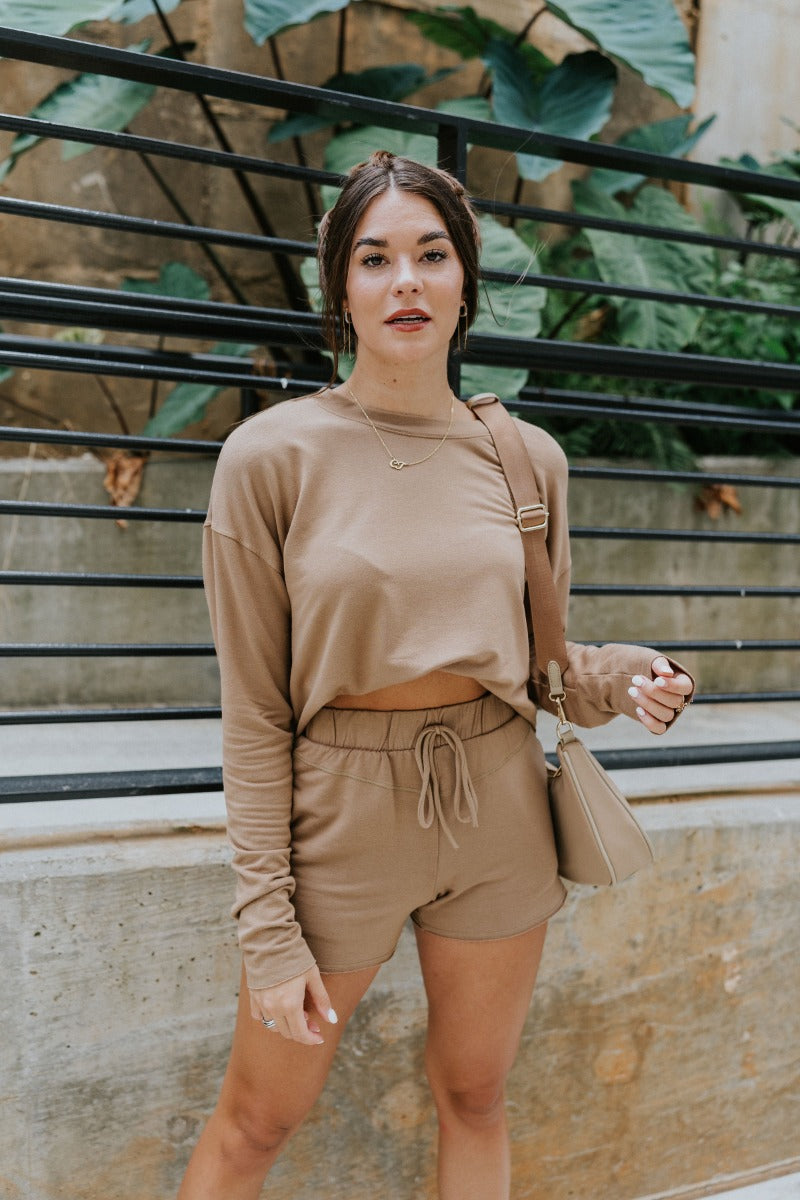 Front view of model wearing the Let's Go Shorts, which feature a thick elastic waist band with a tie, side pockets, a raw edge hem, and a flowy fit. Worn with matching top.