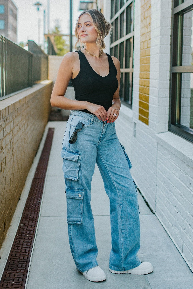 Front view of model wearing the Dakota Cargo Jeans that have blue denim fabric, pockets, a front zipper with a button closure, belt loops and wide legs