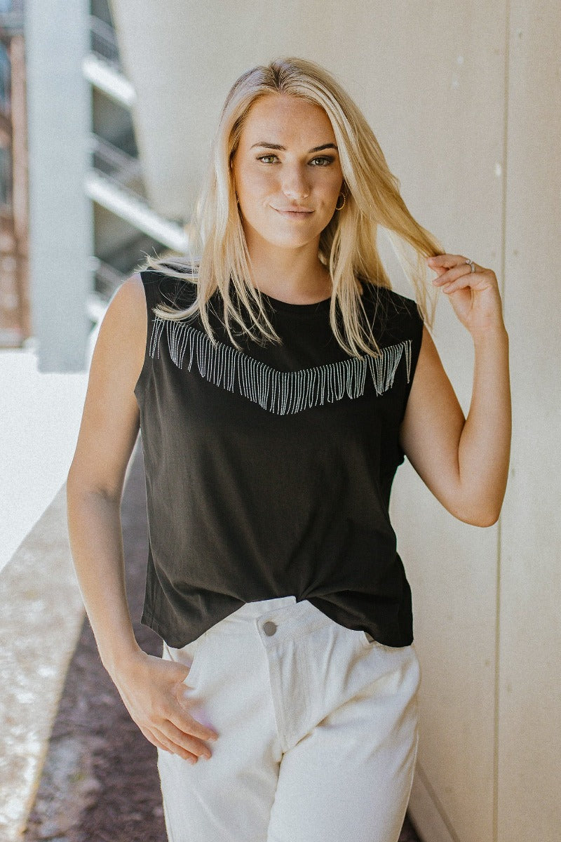 Front view of model wearing the I'm All In Fringe Top that has black knit fabric, a silver beaded fringe design, a round neckline and a sleeveless design
