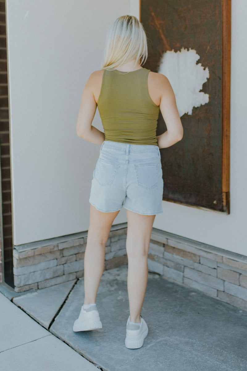 Back view of model wearing the Easy Going Tank Top that features olive green knit fabric, a round neckline and a sleeveless design.