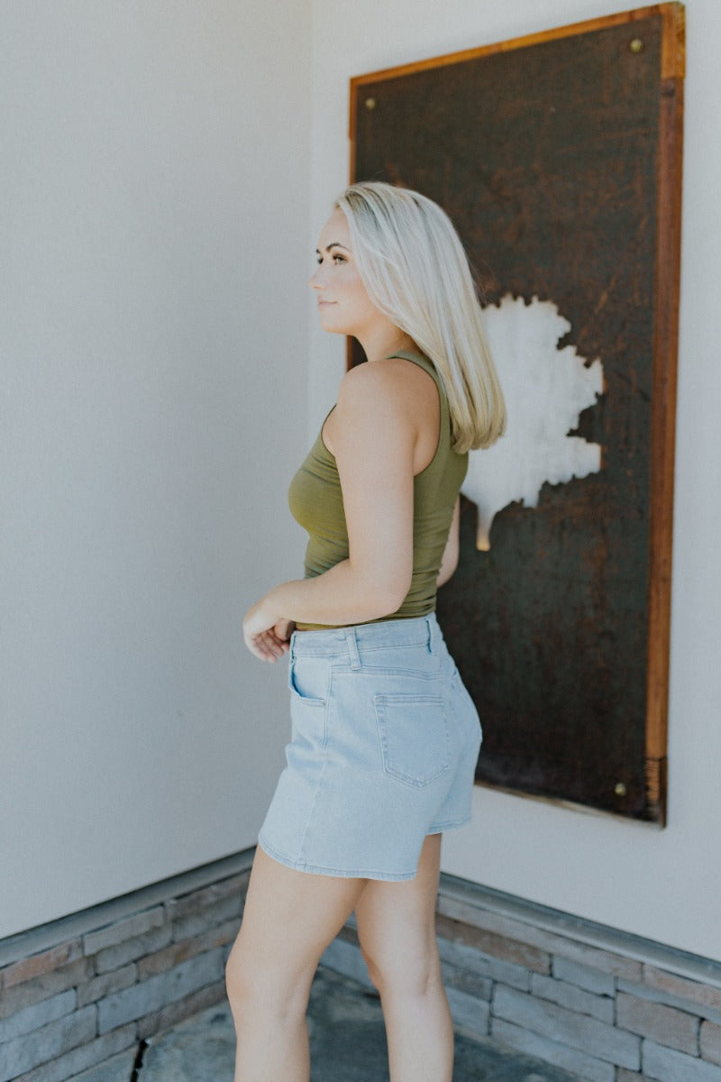 Side view of model wearing the Easy Going Tank Top that features olive green knit fabric, a round neckline and a sleeveless design.