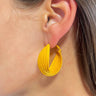 Side view of model wearing the Twisted Up Earrings in Mustard which features matte mustard medium closed hoops with an intertwined design.