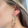 Side view of model wearing the Cheap Thrills Earrings which features scooped, closed hoops with gold lines design.