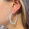 Side view of model wearing the XOXO Open Hoops in Silver which features medium, open hoops with silver beads.