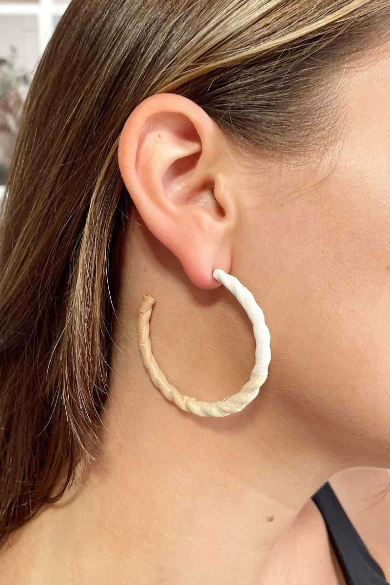 Side view of model wearing the Summer Breeze Earrings which features open, large hoops wrapped in white, beige and cream paper.
