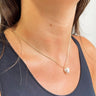 Close up view of model wearing the Heart of Gold Pearl Necklace which features gold chain link with a heart shaped pearl medallion.