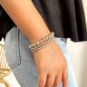 Front view of model wearing the Half and Half Bracelet in Light Pink which features three stack of stretchy bracelets with small gold beads, small light pink beads and large light pink beads.