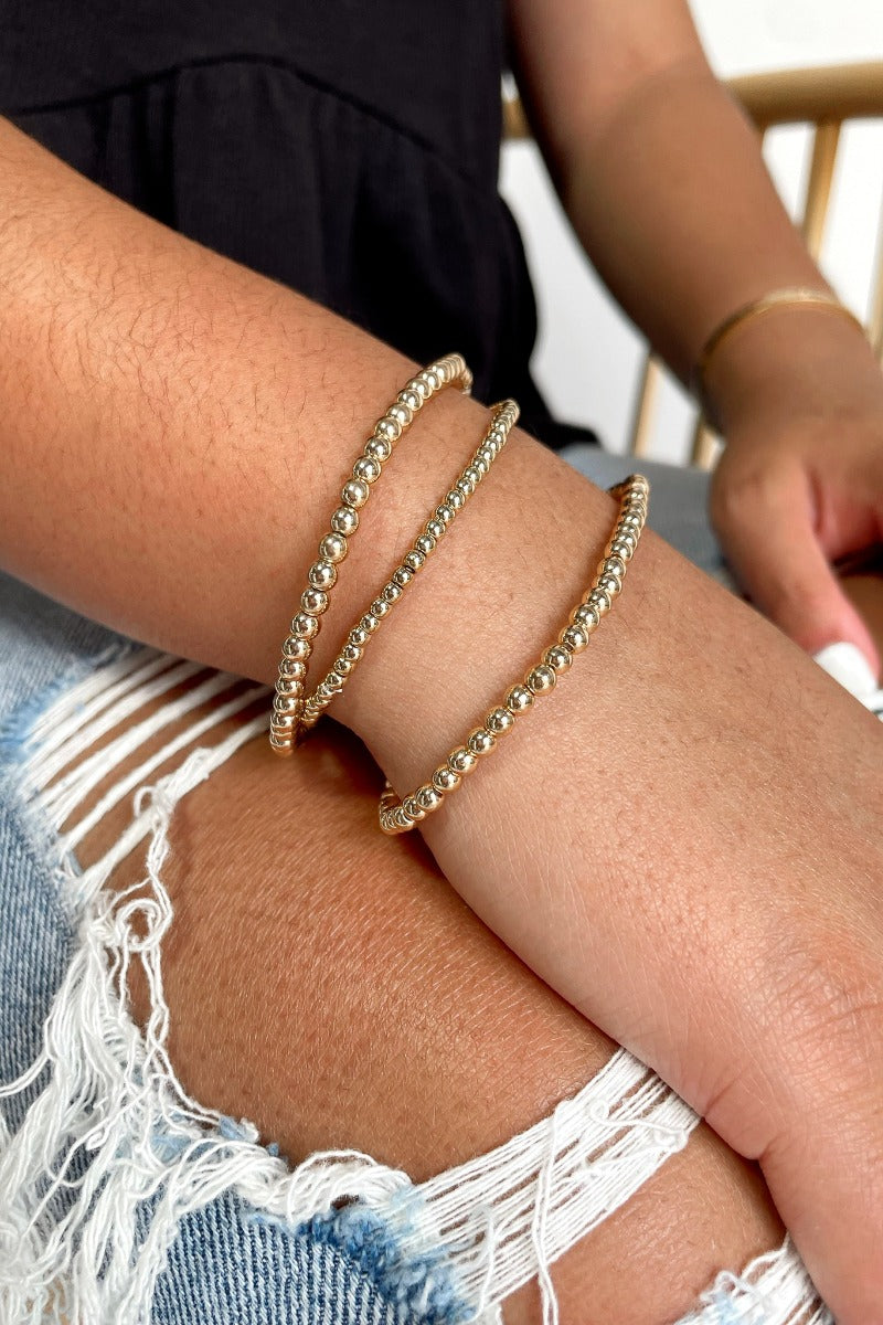 Front view of model wearing the Wear Everyday Bracelet Set which features a three-layered stretch bracelet stack with shiny gold small and medium beads.