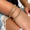 Front view of model wearing the Wear Everyday Bracelet Set which features a three-layered stretch bracelet stack with shiny gold small and medium beads.