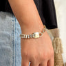 Front view of model wearing the Keep A Secret Bracelet which features clear rectangle stones set in gold linked with a gold lock design and adjustable gold chain link closure.