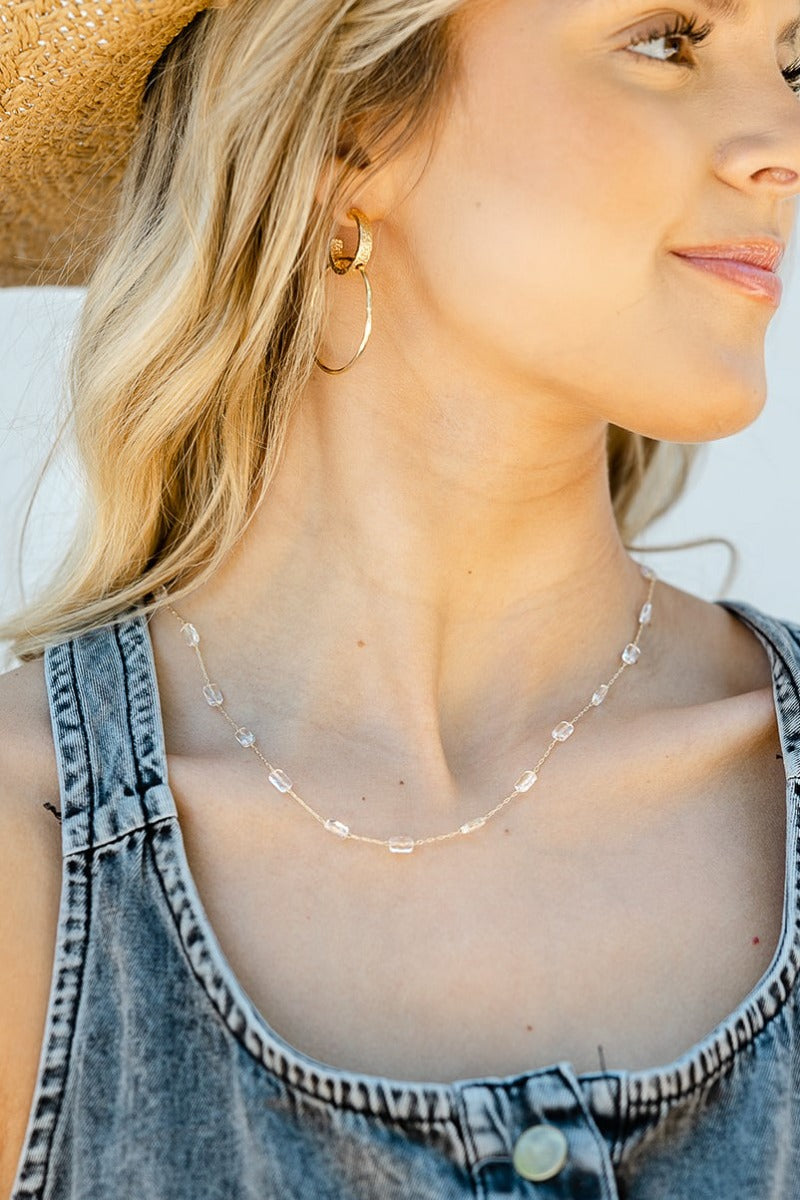 Close up of model wearing the Clear As Day Necklace that has a gold link chain with clear beads.