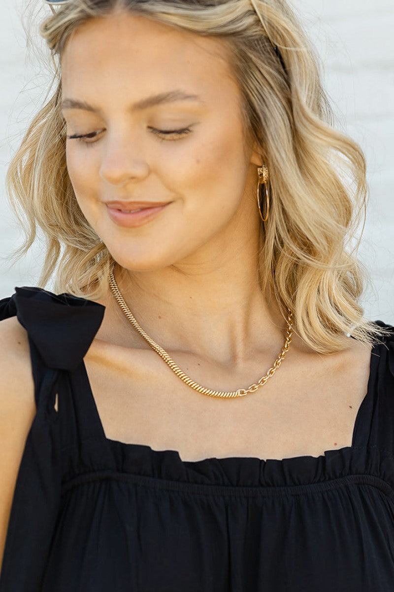 Model is wearing the Half And Half Necklace that has half of a gold chain link with half of a gold braided link.