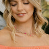 Image of model wearing the Daisy Days Necklace that has a gold link chain with daises, hot pink, and light pink beads.