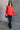 Full body front view of model wearing the Julianna Red Satin Long Sleeve Top that has red satin fabric, a high-low hem, a chest pocket, a notched collar neck, and long sleeves with buttoned cuffs.