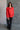 front view of model wearing the Julianna Red Satin Long Sleeve Top that has red satin fabric, a high-low hem, a chest pocket, a notched collar neck, and long sleeves with buttoned cuffs.