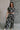 Full body front view of model wearing the Genevieve Black & Cream Printed Wide Leg Pants that have black lightweight fabric with a cream aztec pattern, two side slit pockets, wide legs and an elastic waistband.