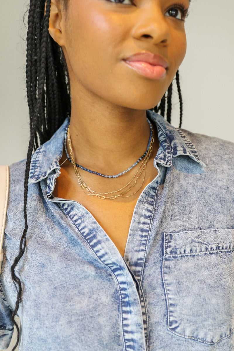 front view of model wearing the Gianna Blue and Gold Layered Necklace that feautures 4 layers: 3 varied gold chains and one blue beaded strand.