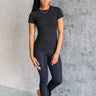 Full body front view of model wearing the Robin Black Athletic Short Sleeve Top that has black athleisure fabric, monochrome stitch details, a scooped neckline, and short sleeves.