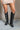 Front view of model wearing the Arcadia Black Western Boots that feature black faux leather, cream western stitching, and black soles with 3 inch heels.