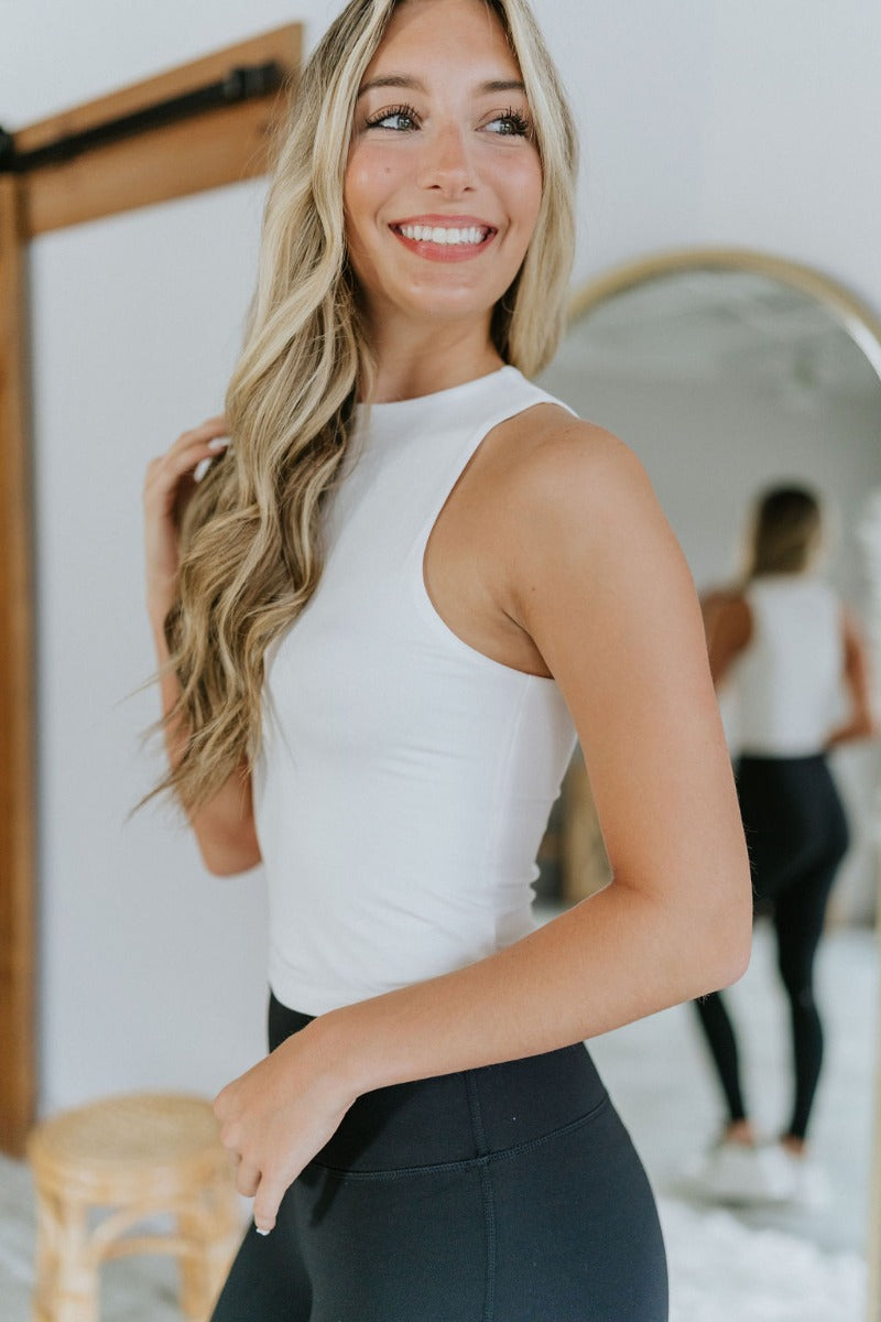 Close up/side view of model wearing the Close To You Tank in Ivory which features ivory knit fabric with a lining, a round neckline, and a sleeveless body.