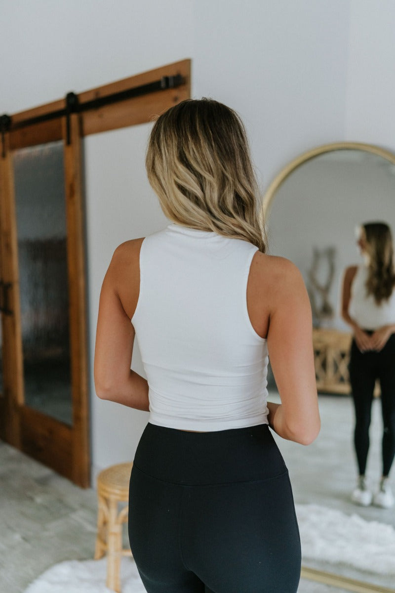 Back view of model wearing the Close To You Tank in Ivory which features ivory knit fabric with a lining, a round neckline, and a sleeveless body.